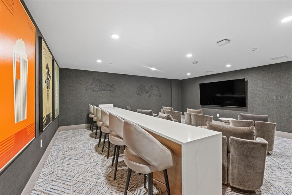 A media room features a long white bar with stools, plush armchairs, and wall art — 6000 PARADISO GRANDE BOULEVARD UNIT B2, ORLANDO, FL