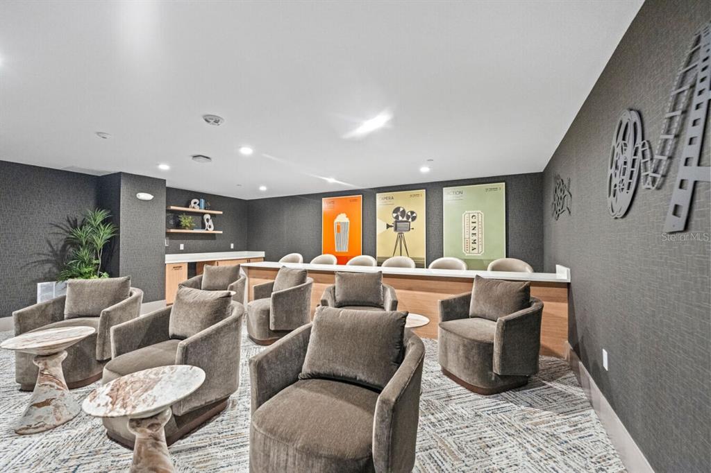 A modern media room features gray armchairs, a bar counter, and cinema-themed wall art — 6000 PARADISO GRANDE BOULEVARD UNIT B2, ORLANDO, FL
