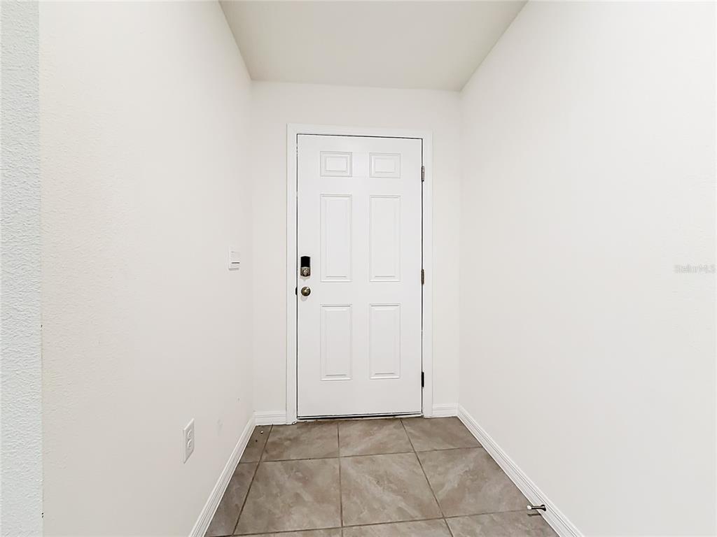 A small entryway features white walls, a white six-panel door, and tiled flooring — 6608 SE 1ST LOOP, OCALA, FL