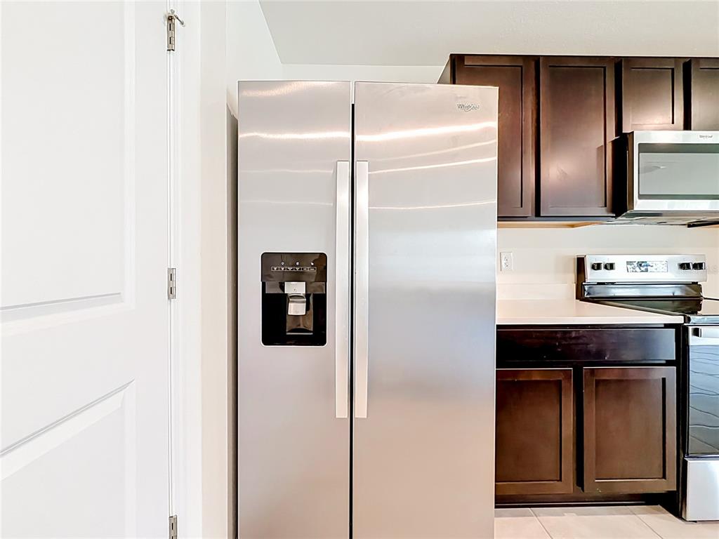 A stainless steel refrigerator stands next to dark wood cabinets in a kitchen — 6608 SE 1ST LOOP, OCALA, FL