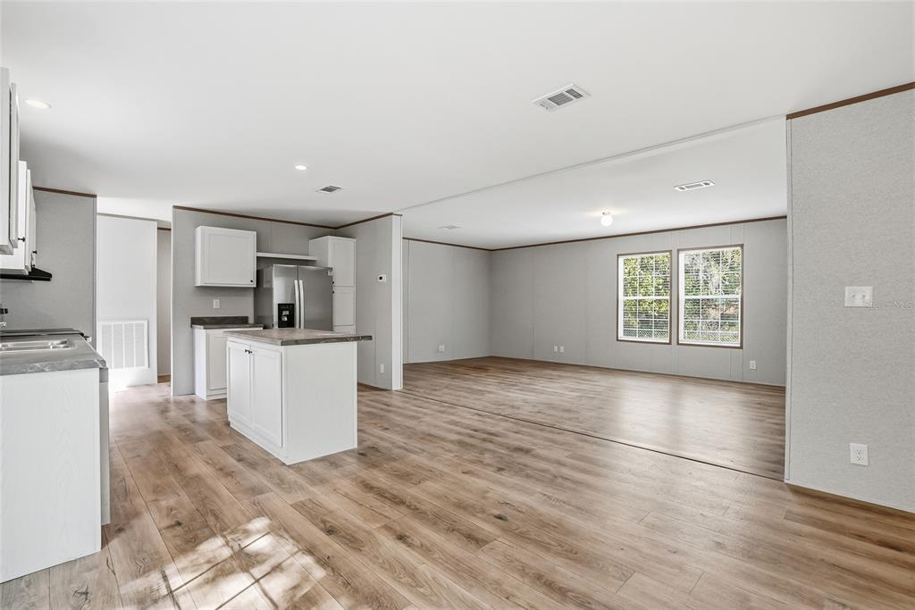An open-concept kitchen and living area with white cabinets, a center island, and wood-look flooring — 12015 WESTBAY AVENUE, NEW PORT RICHEY, FL