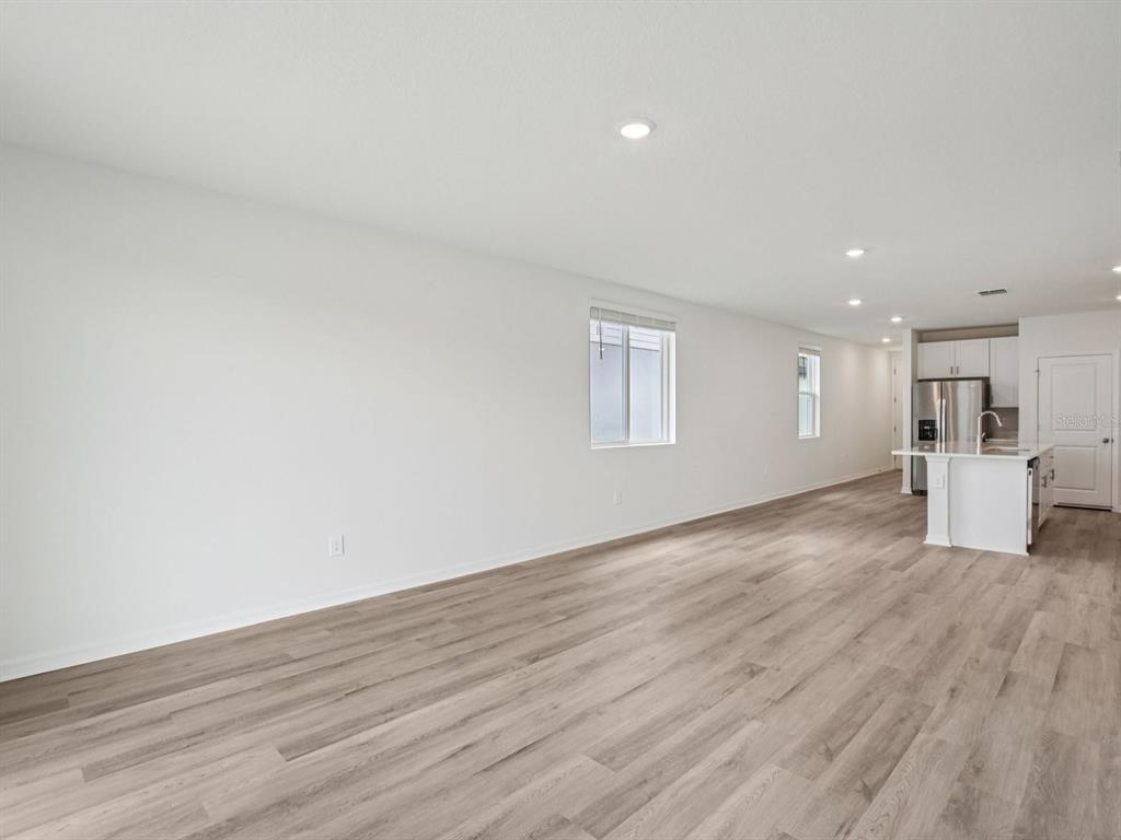 An open-concept living area features white walls, light wood-look flooring, and a modern kitchen — 3744 MOSCATO DRIVE, BROOKSVILLE, FL