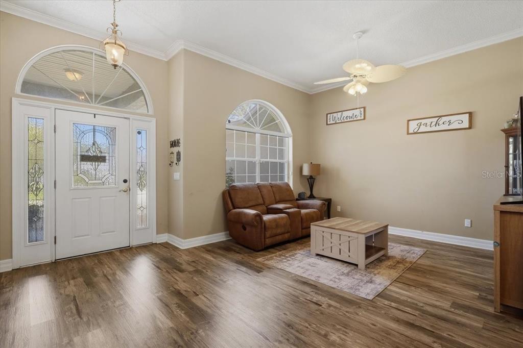 A living and dining area with wood-look flooring, a ceiling fan, and a large window — 56 WESTBURY LANE, PALM COAST, FL