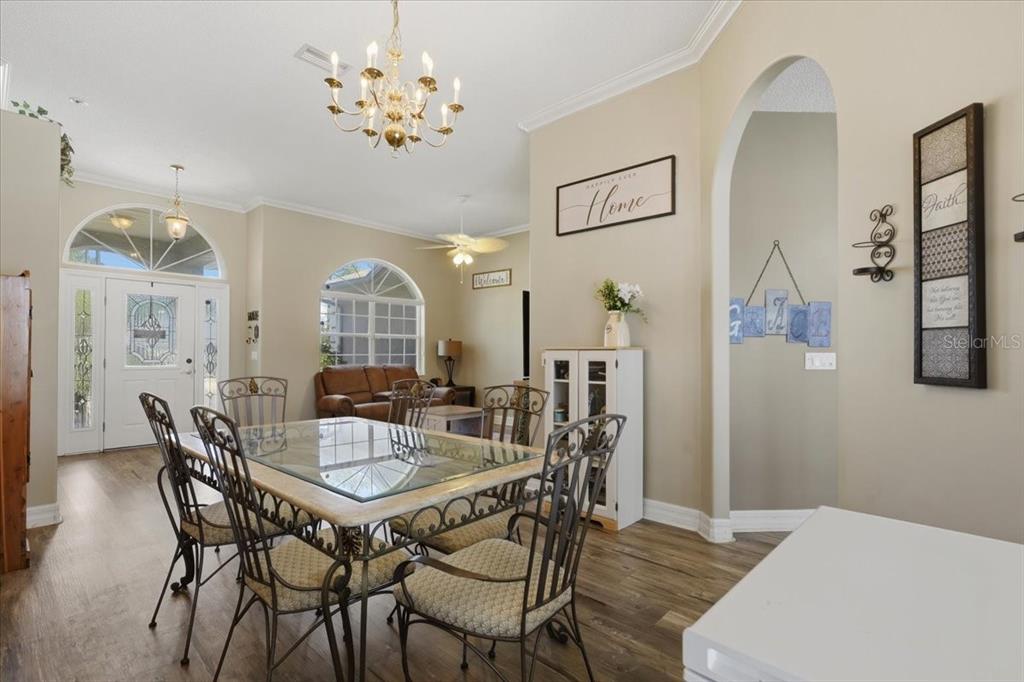 A living room features wood-look flooring, arched windows, a ceiling fan, and a brown loveseat — 56 WESTBURY LANE, PALM COAST, FL