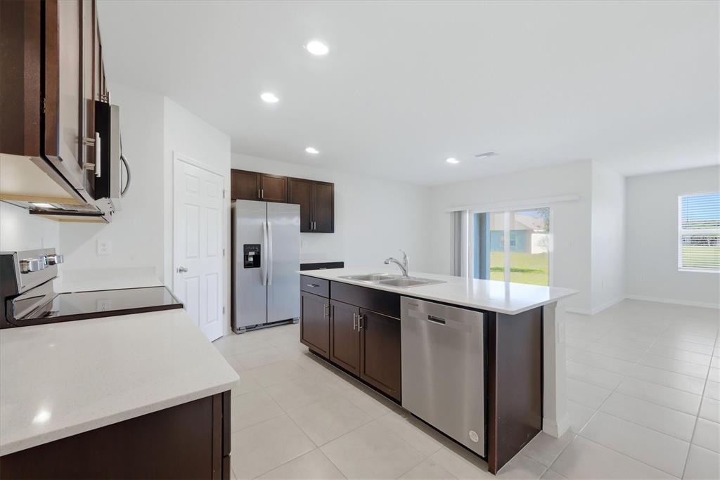 A kitchen features dark wood cabinets, stainless steel appliances, and a white quartz island — 25118 DOREDO DRIVE, PUNTA GORDA, FL