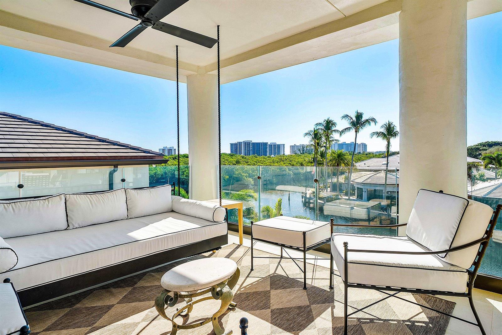 A covered balcony features a hanging sofa, outdoor seating, and a view of a canal — 5344 Boca Marina Circle N, Boca Raton FL 33487, BOCA RATON, FL