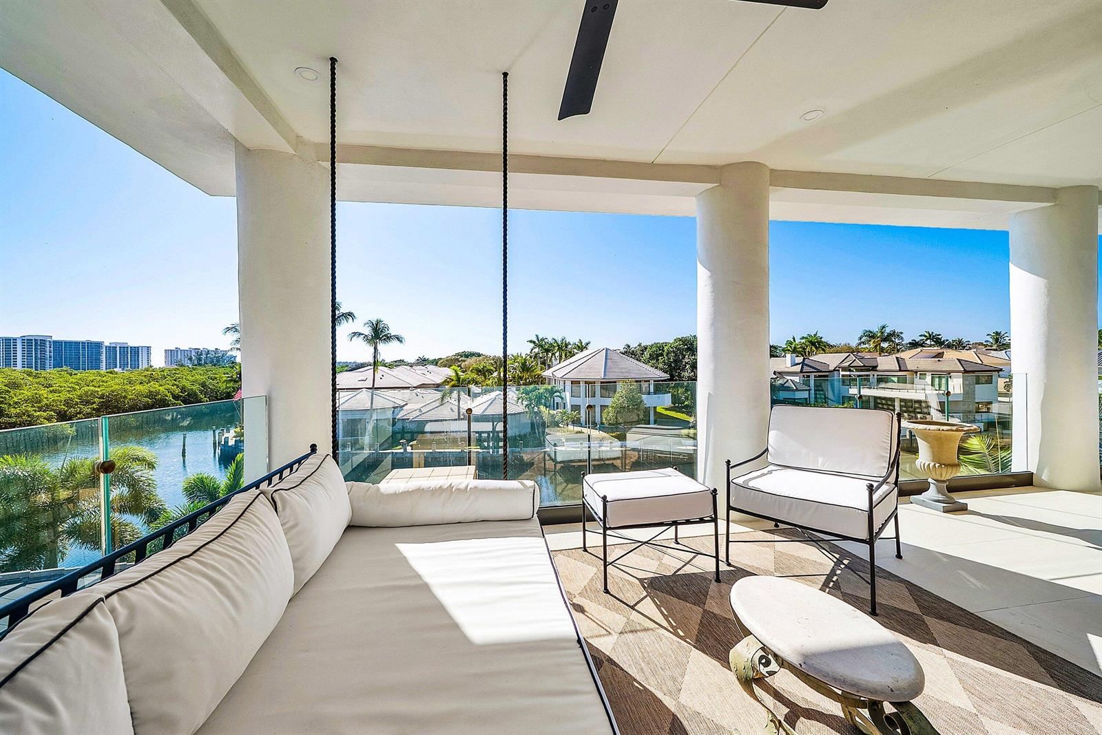 A covered balcony features a hanging daybed, outdoor seating, and a glass railing overlooking water — 5344 Boca Marina Circle N, Boca Raton FL 33487, BOCA RATON, FL