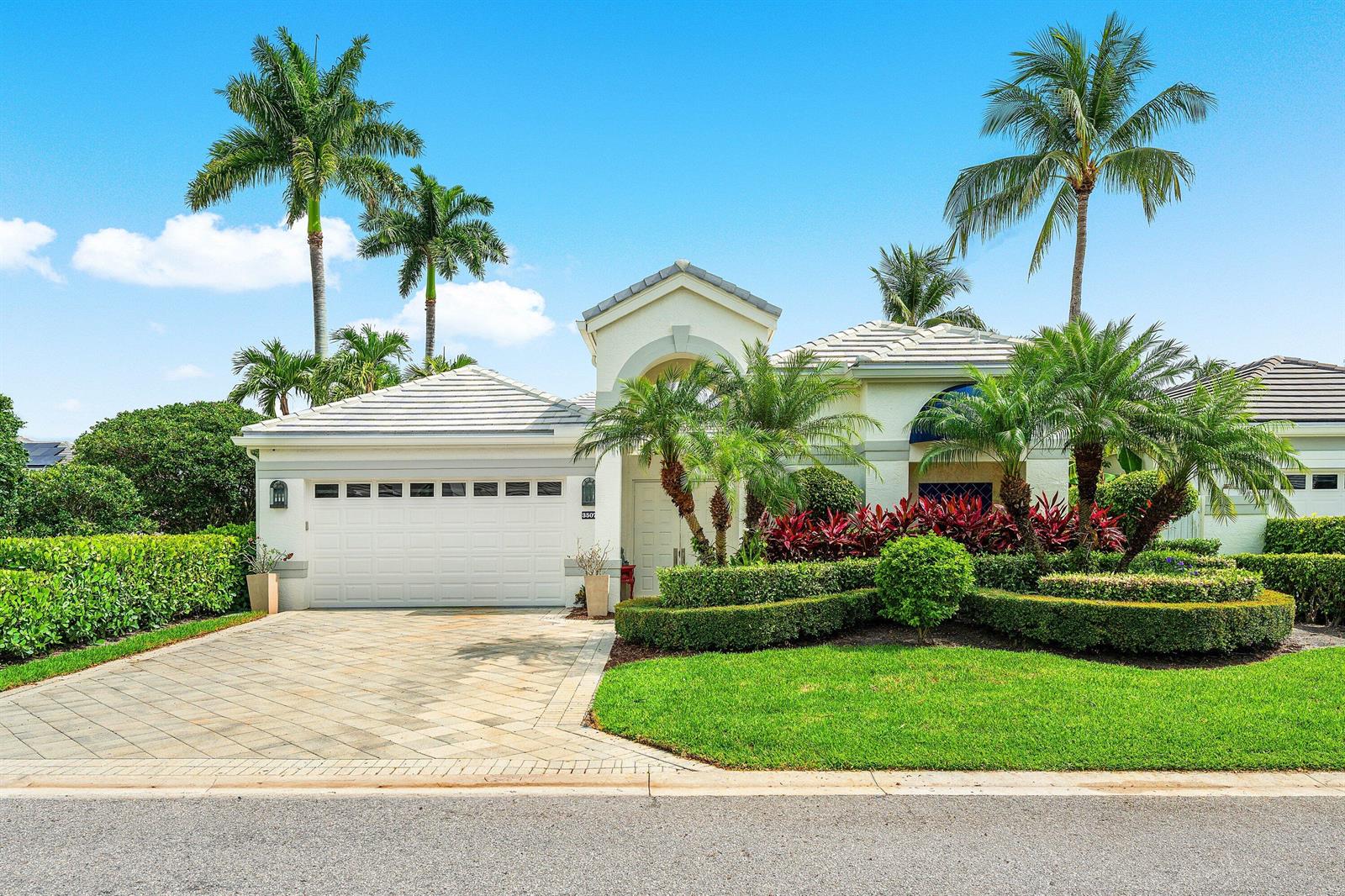 A single-story house with a white garage, paved driveway, and manicured landscaping under a blue sky — 3507 NW Clubside Circle, Boca Raton FL 33496, BOCA RATON, FL