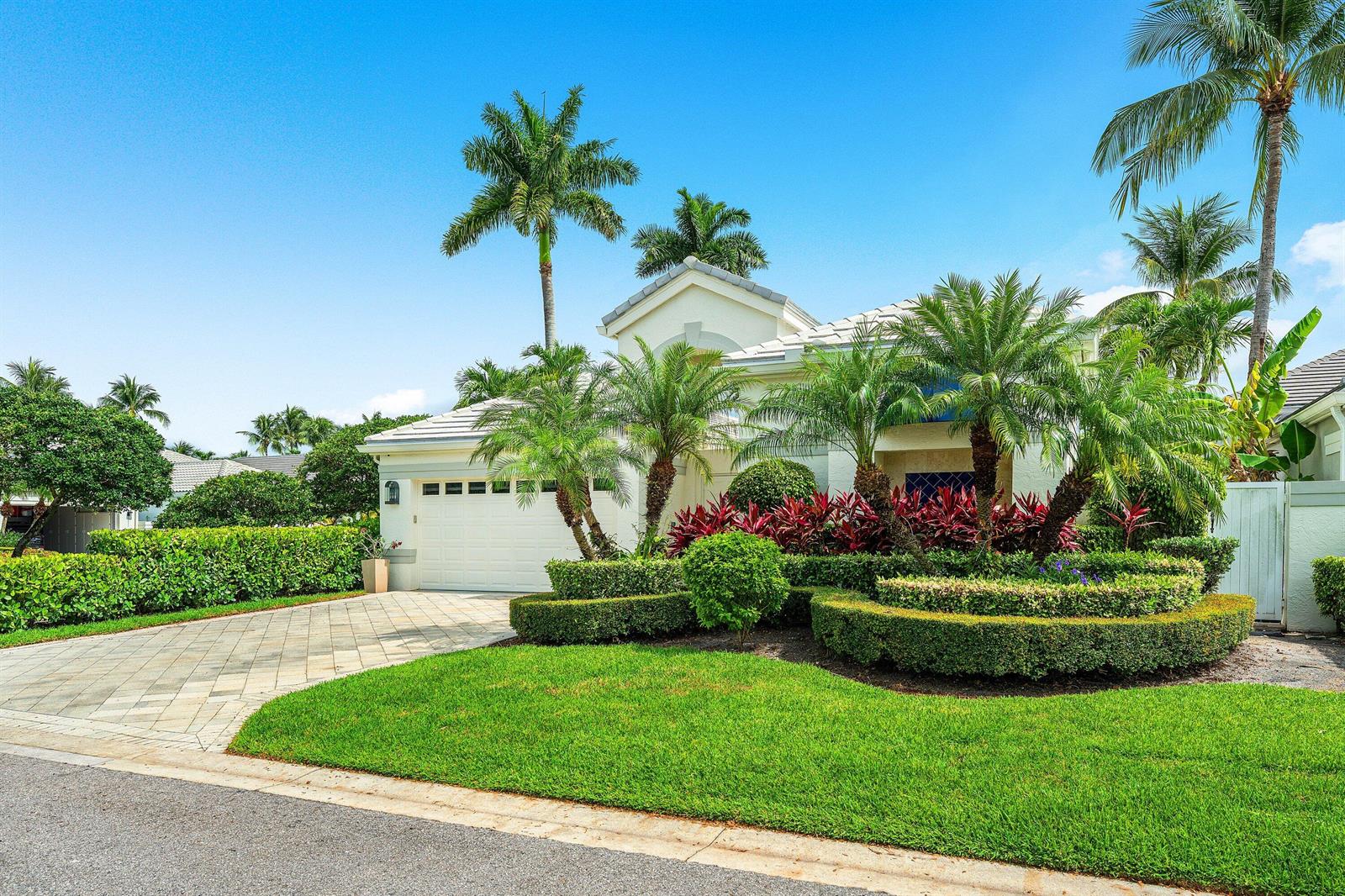 A single-story house with a paved driveway, manicured hedges, and palm trees under a blue sky — 3507 NW Clubside Circle, Boca Raton FL 33496, BOCA RATON, FL