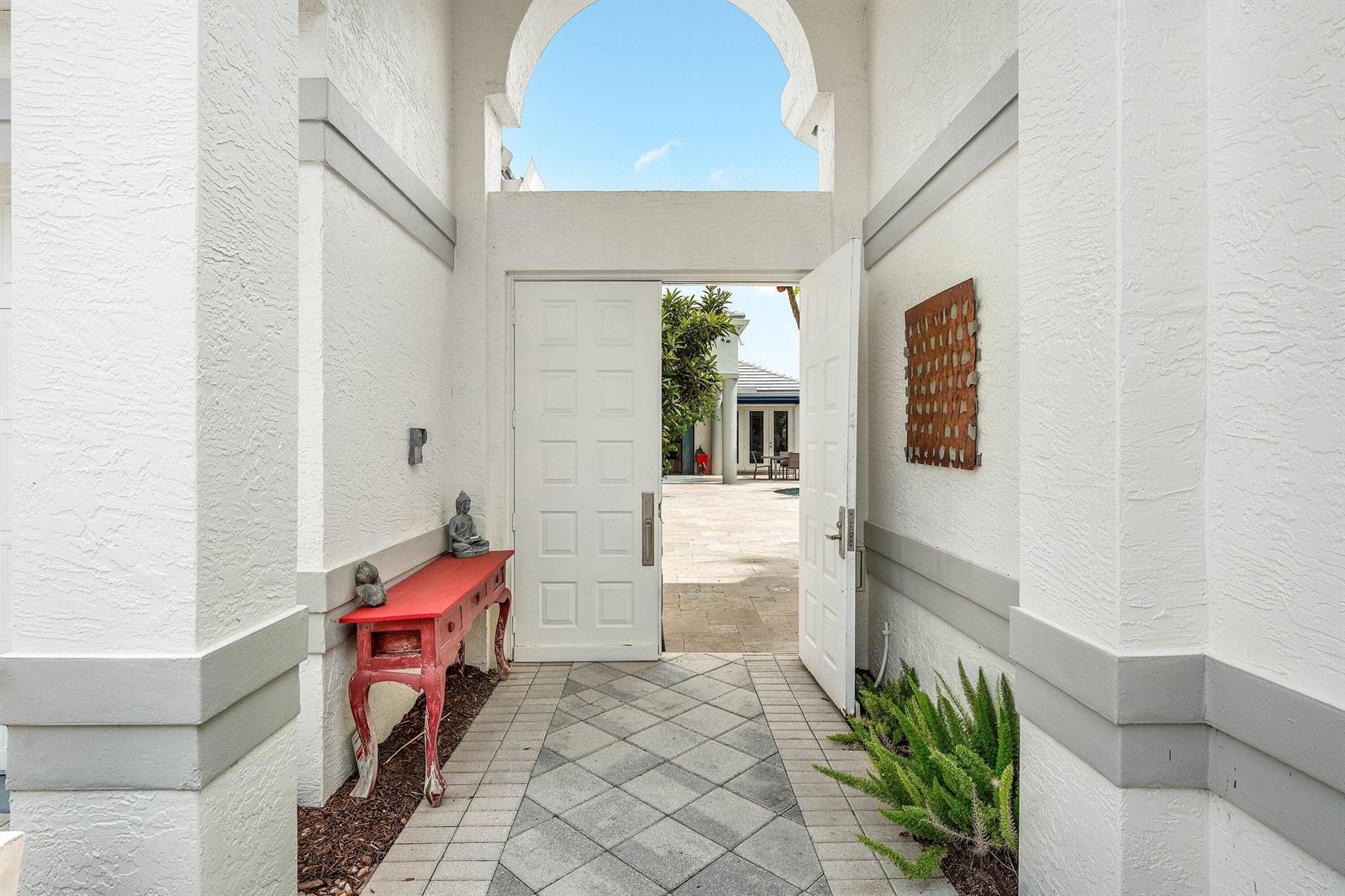 An open double door leads from a tiled entryway into a sunny outdoor courtyard — 3507 NW Clubside Circle, Boca Raton FL 33496, BOCA RATON, FL