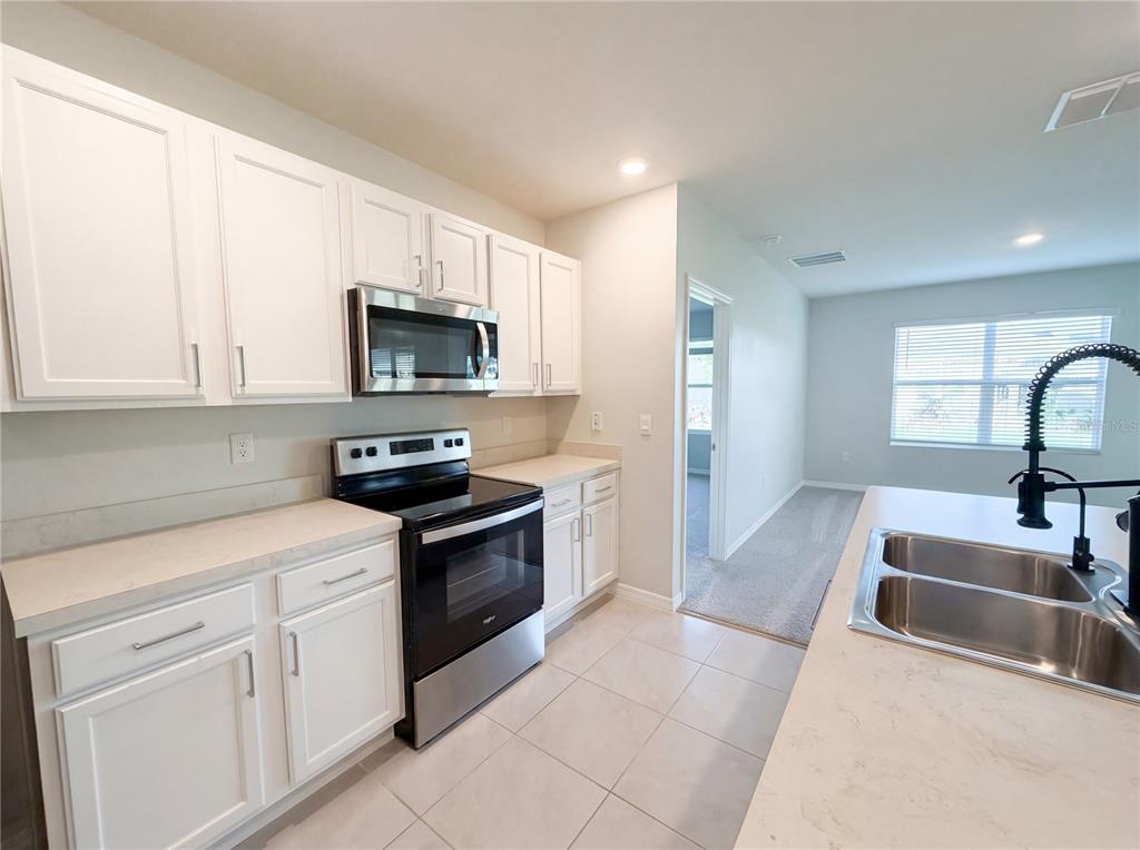 A kitchen with white cabinets, stainless steel appliances, and a double-basin sink — 1818 IRBY COURT, TAVARES, FL