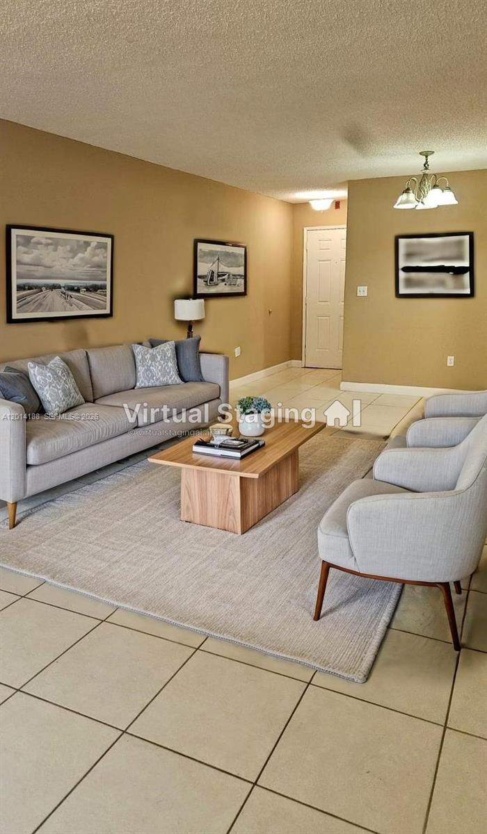 This virtually staged living room features a gray sofa, two armchairs, and a wooden coffee table — 6801 Harding Ave # 217, Miami Beach FL 33141, MIAMI BEACH, FL
