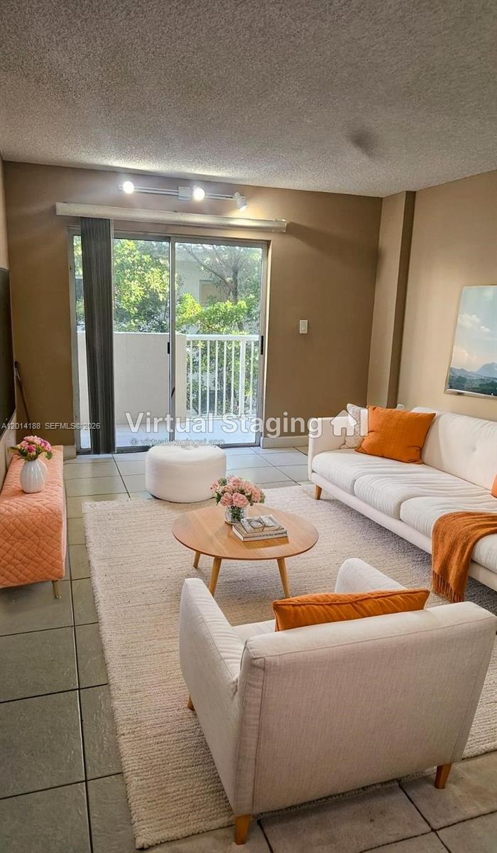 This living room features tile flooring, a white sofa, and a sliding glass balcony door — 6801 Harding Ave # 217, Miami Beach FL 33141, MIAMI BEACH, FL