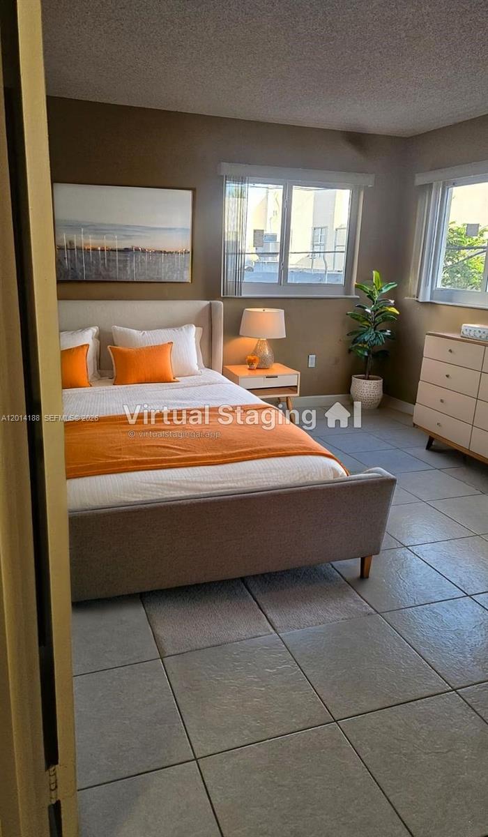 This bedroom features a bed with orange accents, a nightstand, a dresser, and tiled floors — 6801 Harding Ave # 217, Miami Beach FL 33141, MIAMI BEACH, FL