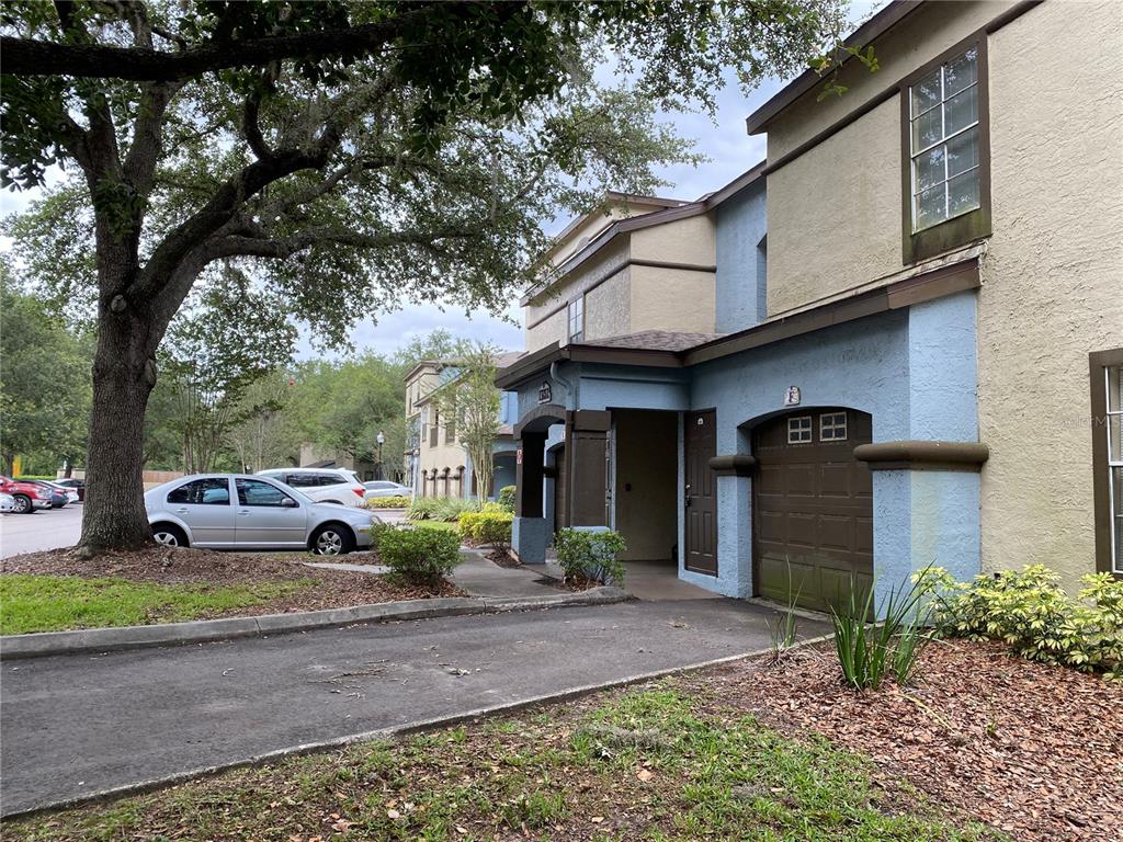 A two-story townhouse exterior features a blue stucco facade, a single-car garage, and a driveway — 13212 ARBOR ISLE DRIVE UNIT 201, TAMPA, FL