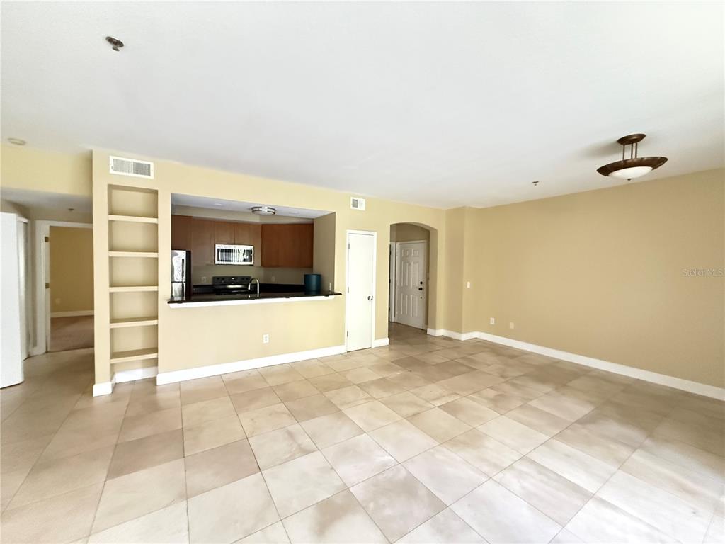 An open-concept living area features light-colored tile floors, beige walls, and a kitchen pass-through — 13212 ARBOR ISLE DRIVE UNIT 201, TAMPA, FL