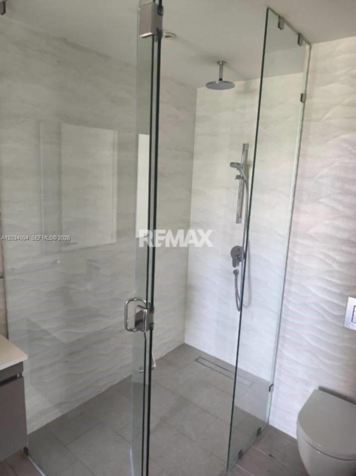 A modern bathroom features a glass-enclosed walk-in shower with textured white tile walls — 1 la altagracia # 0, FL