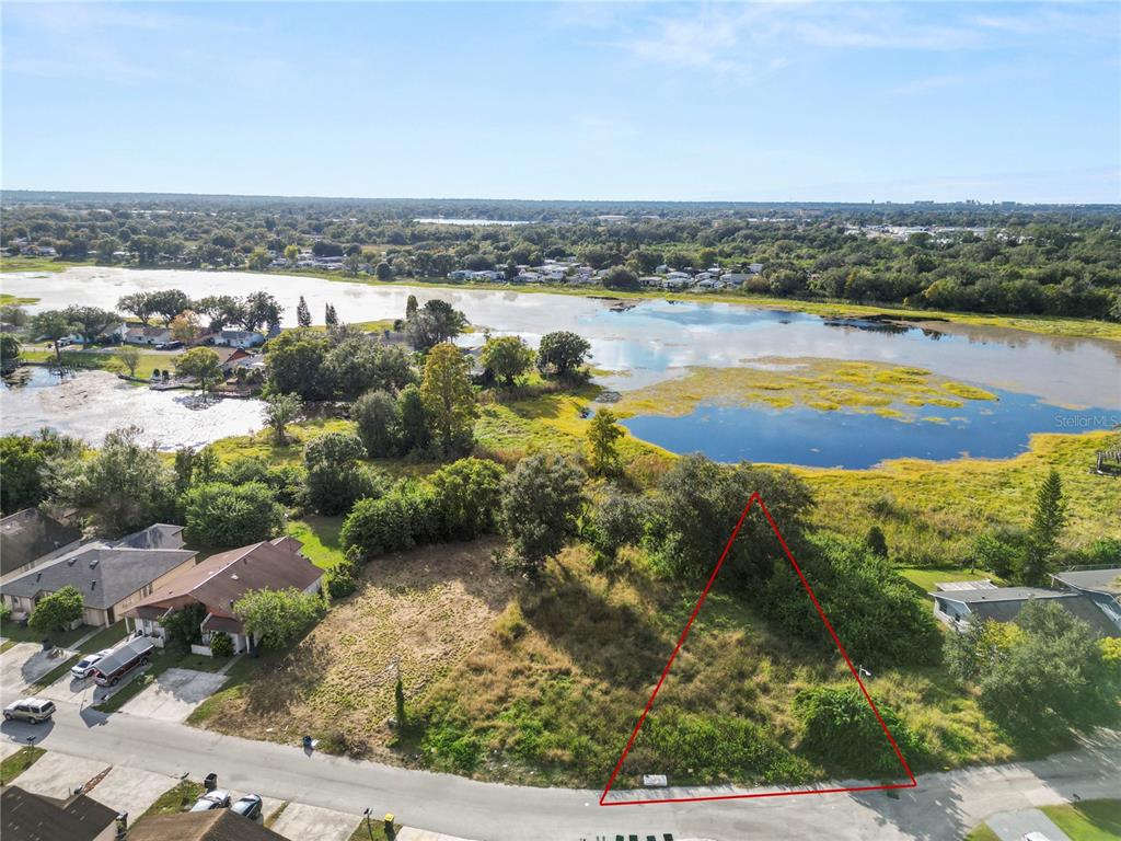 An aerial view shows a vacant, triangular-shaped lot situated next to a lake — CAPTIVA POINT, LAKELAND, FL