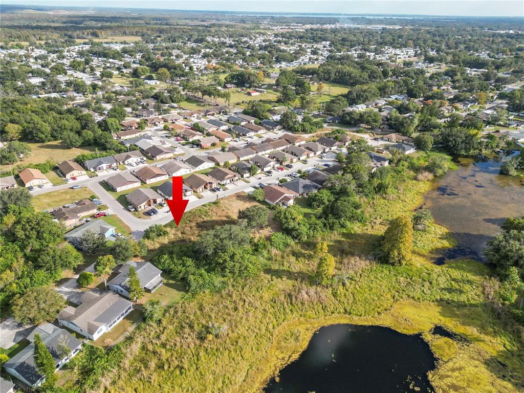 An aerial view shows a vacant residential lot marked by a red arrow near water — CAPTIVA POINT, LAKELAND, FL