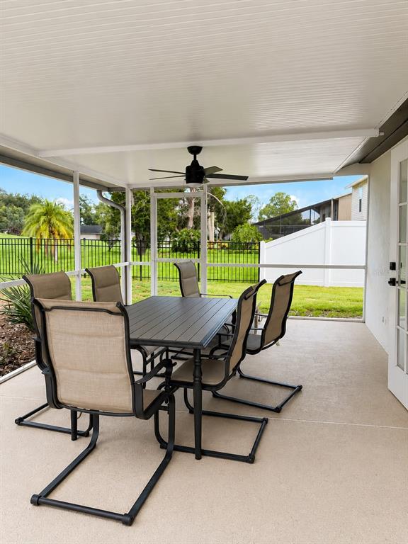 A screened-in patio features a dining set, a ceiling fan, and a view of grass — 16209 W COURSE DRIVE, TAMPA, FL