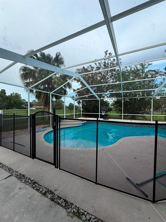 A swimming pool with a safety fence is enclosed by a screened-in lanai — 16209 W COURSE DRIVE, TAMPA, FL