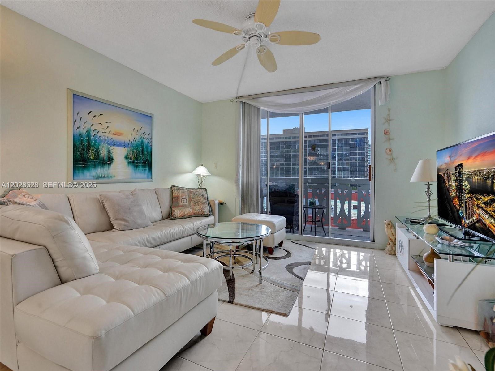 A living room features a white sectional sofa, glass coffee table, and sliding glass balcony doors — 3113 S Ocean Dr # 603, Hallandale Beach FL 33009, HALLANDALE BEACH, FL
