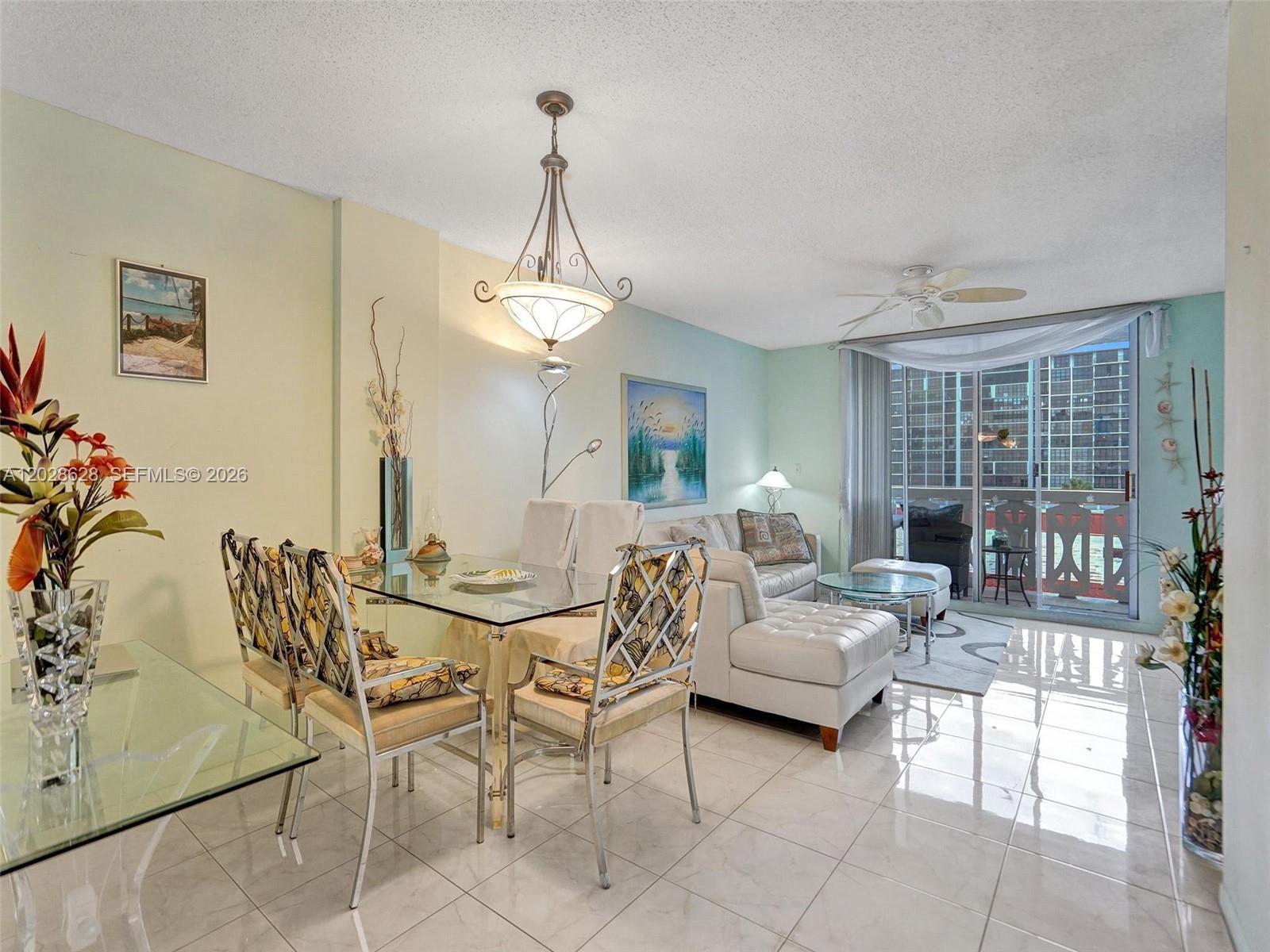 A dining area and living room with tile floors, a glass table, and balcony access — 3113 S Ocean Dr # 603, Hallandale Beach FL 33009, HALLANDALE BEACH, FL