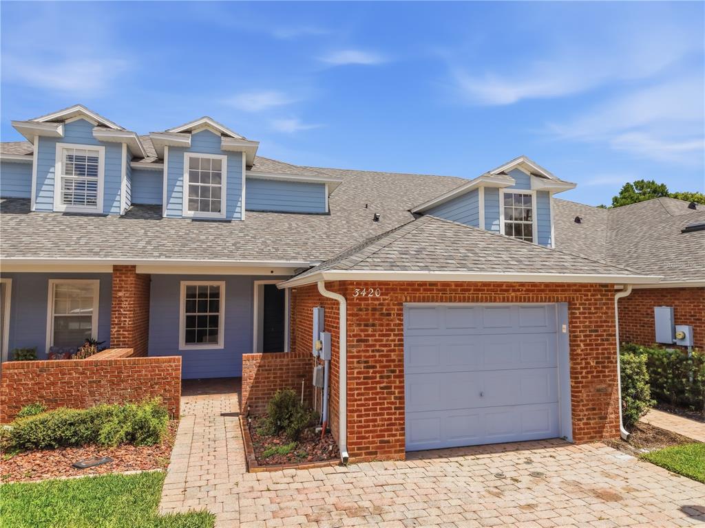 A two-story blue house with a brick facade, a single-car garage, and a paved walkway — 3420 HOME TOWN LANE, ST CLOUD, FL