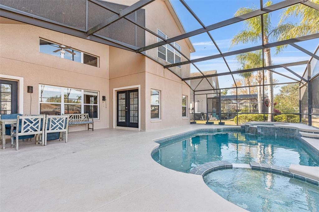 A screened-in patio features a swimming pool, a hot tub, and outdoor seating — 8019 ACADIA ESTATES COURT, KISSIMMEE, FL