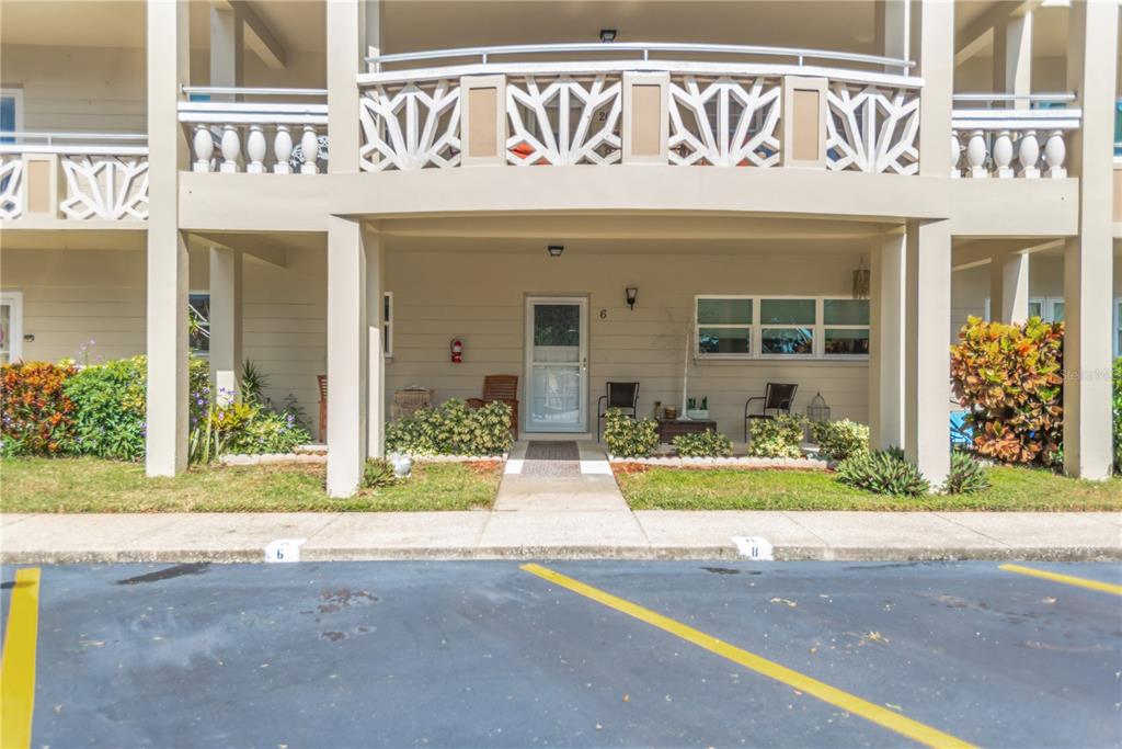 A ground-level apartment entrance with a white door, patio furniture, and a parking space — 2350 HAITIAN DRIVE UNIT 6, CLEARWATER, FL