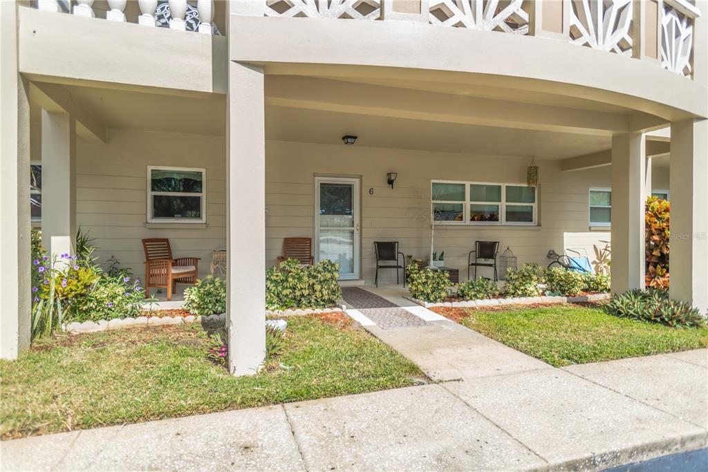 A covered patio area features a front door, seating, and landscaping in front of a building — 2350 HAITIAN DRIVE UNIT 6, CLEARWATER, FL