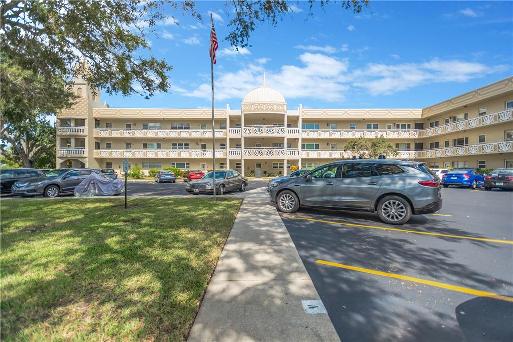 A multi-story apartment building with a central dome stands behind a parking lot — 2350 HAITIAN DRIVE UNIT 6, CLEARWATER, FL