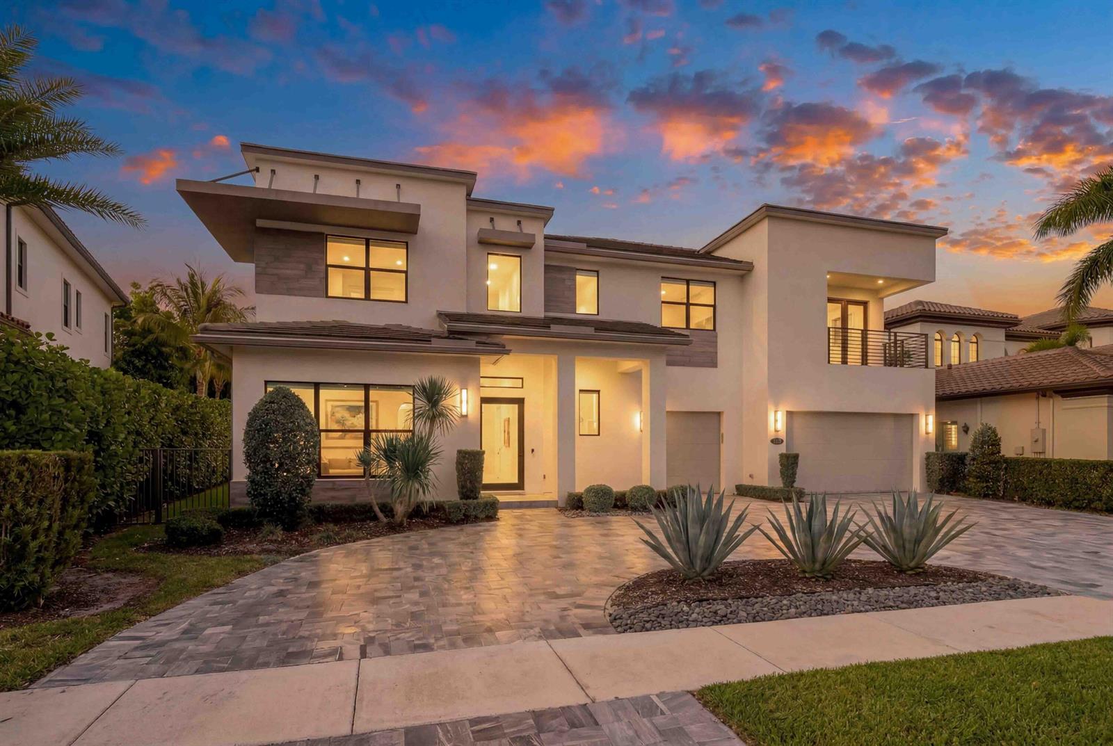 A two-story modern house with a paved driveway, stucco exterior, and a sunset sky — 17558 Cadena Drive, Boca Raton FL 33496, BOCA RATON, FL