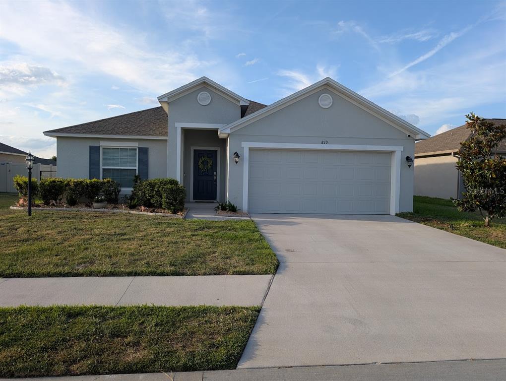 A single-story house with a gray exterior, a two-car garage, and a front lawn — 819 CHANNING STREET, WINTER HAVEN, FL