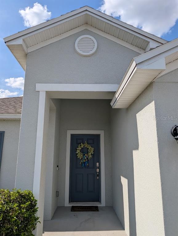 A front exterior view of a house featuring a dark blue door and a wreath — 819 CHANNING STREET, WINTER HAVEN, FL