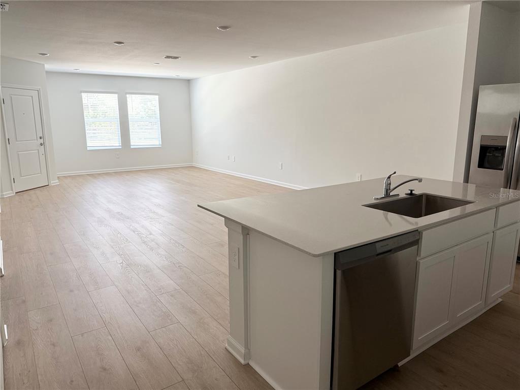 A kitchen island with a sink and dishwasher overlooks an open-concept living area — 5178 CLAY WHALEY ROAD, ST CLOUD, FL