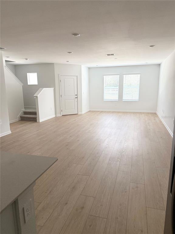 An open-concept living area features light wood-look flooring, recessed lighting, and a white front door — 5178 CLAY WHALEY ROAD, ST CLOUD, FL