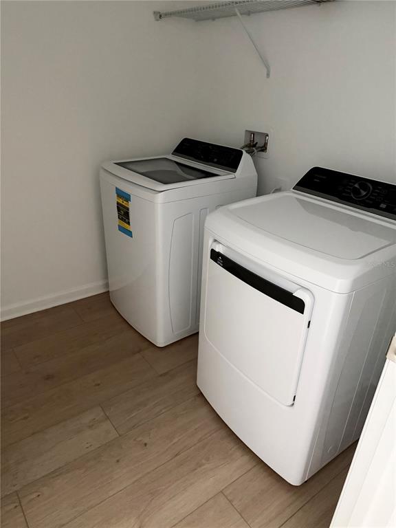 A laundry room features a white washer and dryer on light wood-look flooring — 5178 CLAY WHALEY ROAD, ST CLOUD, FL