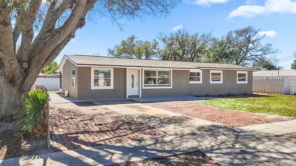 A single-story house with a brown stucco exterior, a white front door, and brick driveway — 4418 W FAIRVIEW HEIGHTS, TAMPA, FL