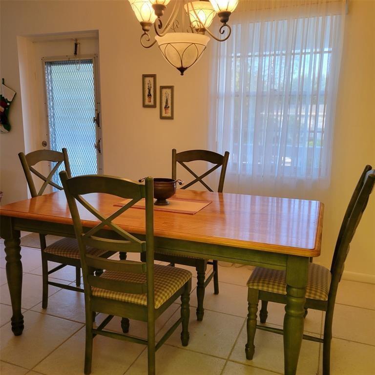 A dining room features a wooden table with green chairs and a chandelier overhead — 351 Markham P # 351, Deerfield Beach FL 33442, DEERFIELD BEACH, FL