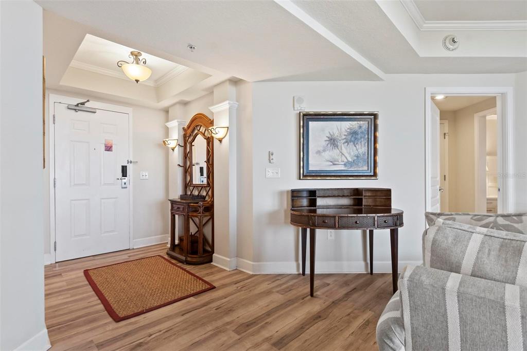 An entryway features wood-look flooring, a white front door, a wooden hall tree, and a desk — 200 OCEAN CREST DRIVE UNIT 705, PALM COAST, FL