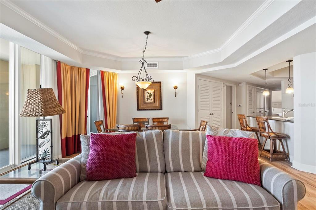 A living room with a striped sofa, dining area, and kitchen counter with bar stools — 200 OCEAN CREST DRIVE UNIT 705, PALM COAST, FL