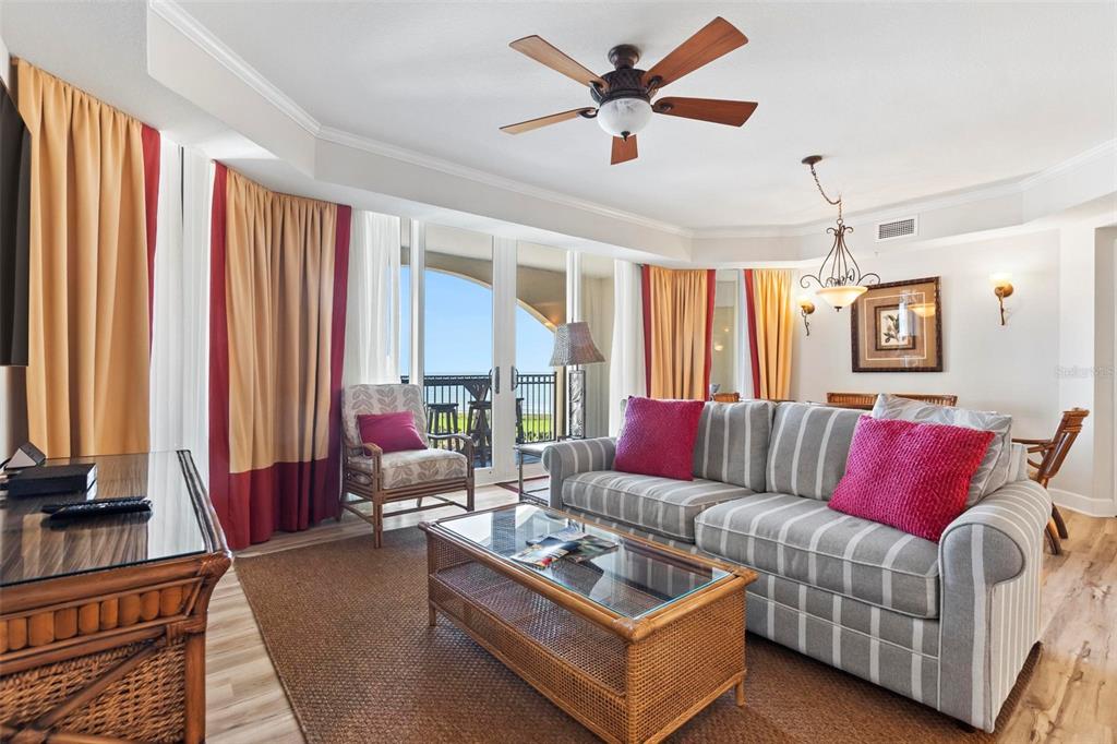 A living room with a striped sofa, wicker coffee table, and a balcony view — 200 OCEAN CREST DRIVE UNIT 705, PALM COAST, FL