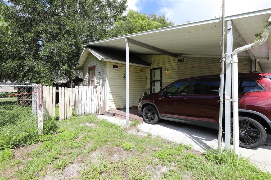 A small house with yellow siding features a carport and a fenced yard — 2747 EATON AVENUE, LAKELAND, FL