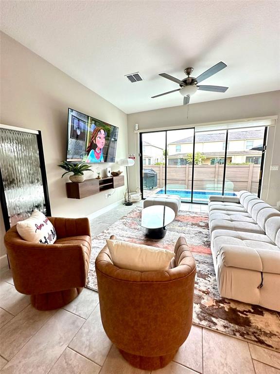 A living room features two brown armchairs, a large sectional sofa, and a wall-mounted television — 136 VILLA DOMANI CIRCLE, DAVENPORT, FL