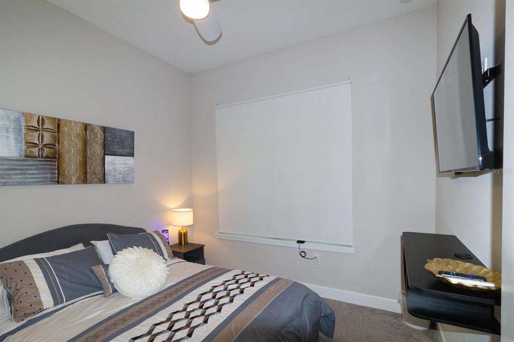 A bedroom features a bed with patterned bedding, a wall-mounted television, and a window — 136 VILLA DOMANI CIRCLE, DAVENPORT, FL