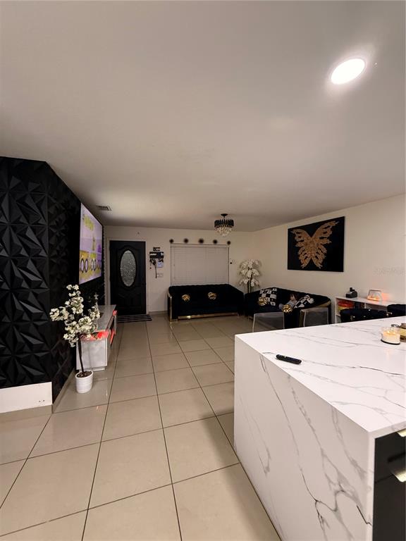 A modern living room features a marble kitchen island, black textured wall, and tile flooring — 1305 E LOUISE AVENUE, TAMPA, FL