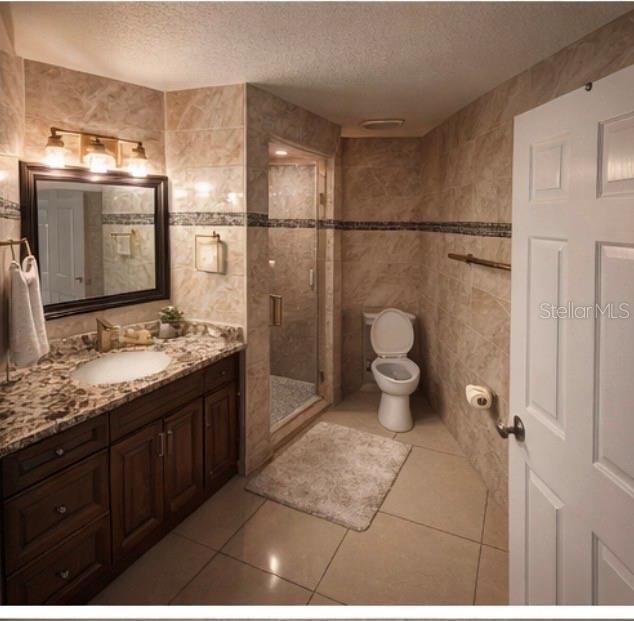 A bathroom features a dark wood vanity, a tiled shower, and a toilet on tiled floors — 1305 E LOUISE AVENUE, TAMPA, FL