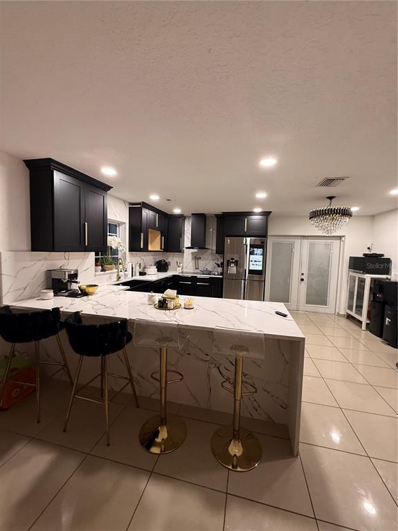 A modern kitchen features black cabinets, white marble-patterned countertops, and a breakfast bar with stools — 1305 E LOUISE AVENUE, TAMPA, FL