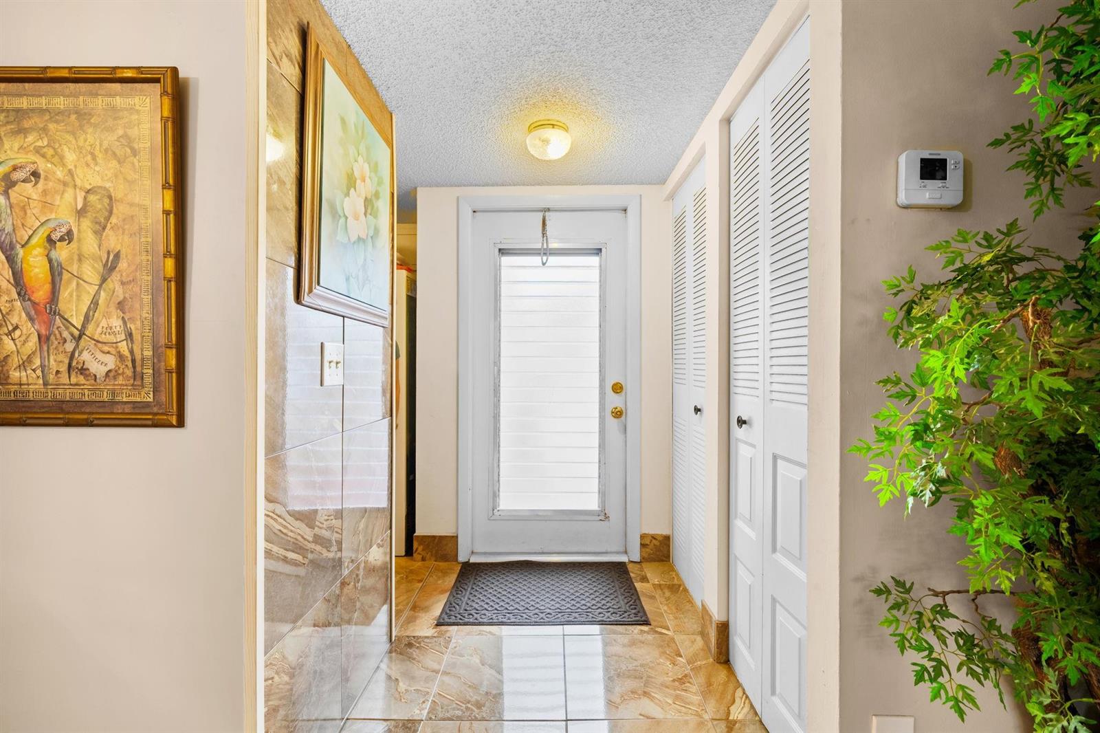An entryway features tiled floors, a white door with a window, and louvered closet doors — 10 Willowbrook Lane # 108, Delray Beach FL 33446, DELRAY BEACH, FL